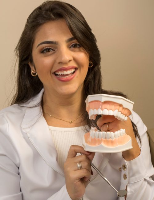 Dentist,Smiling,With,A,Typodont.,She,Hands,Dental,Model,To
